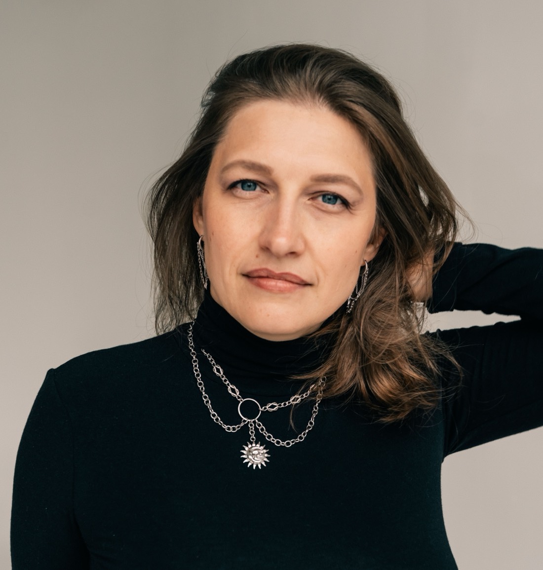 Елена Ревнивцева — крупный портрет: чёрная водолазка, рука за головой, спокойный прямой взгляд